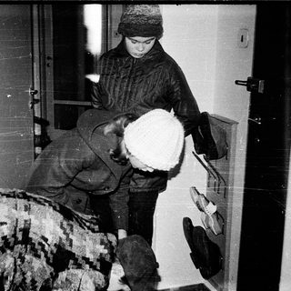 Person carrying large white dog indoors through doorway.