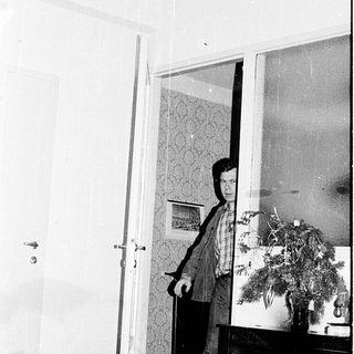 Person standing in doorway holding open door.