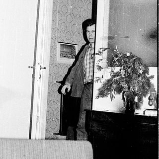 Person standing in doorway holding open door.
