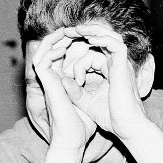 Person covering face with hands indoors.