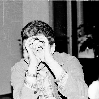 Person covering face with hands indoors.