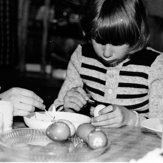 Young girl peeling and cutting boiled eggs.