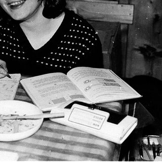 Young girl writing at a table with books.