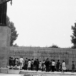 Statue honoring victims with memorial wall.