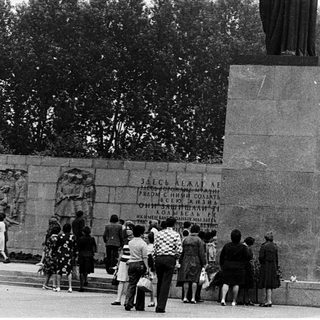 Statue honoring victims with memorial wall.
