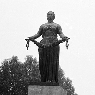 Statue honoring victims with memorial wall.