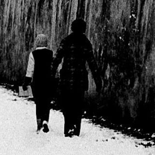 Snowy urban path with people snowboarding.