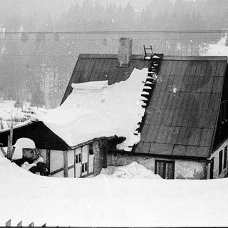 Snow-covered alpine houses with damaged roofs.