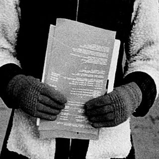 Child holding book on snowy urban street.