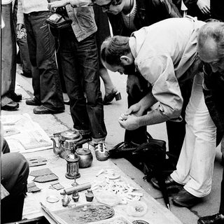Cobbler repairing shoes on street.