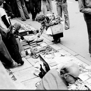 People sorting and examining discarded items on street.