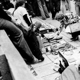 People sorting and examining discarded items on street.