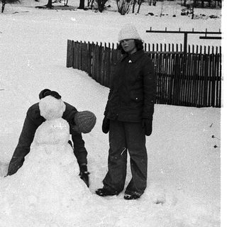 Two people building snow sculpture in winter.