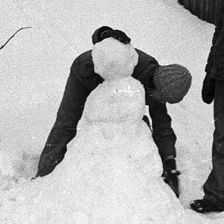Two people building snow sculpture in winter.