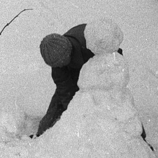 Snowman building in winter backyard scene.