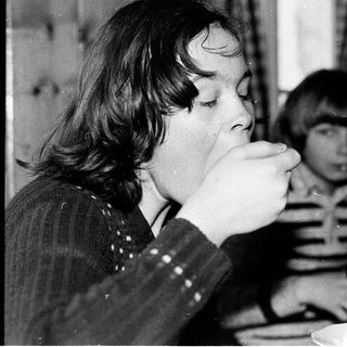 Two children drinking at a table indoors.