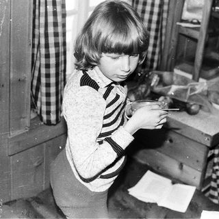 Young girl cutting food at kitchen counter.
