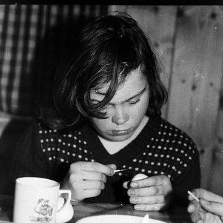 Person eating soup with spoon indoors.