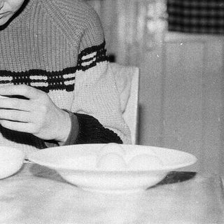 Person peeling potatoes indoors at a table.