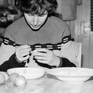 Person peeling potatoes indoors at a table.