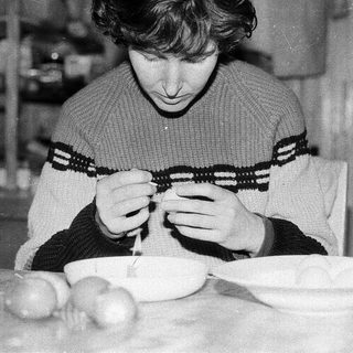 Person peeling potatoes indoors at a table.