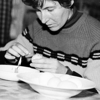 Person meticulously painting or decorating a ceramic bowl.