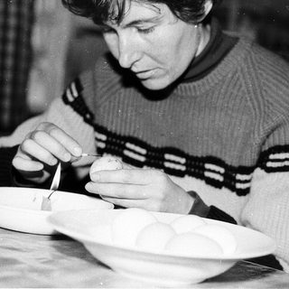 Person meticulously painting or decorating a ceramic bowl.