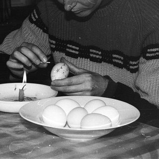 Person decorating Easter eggs with a candle.