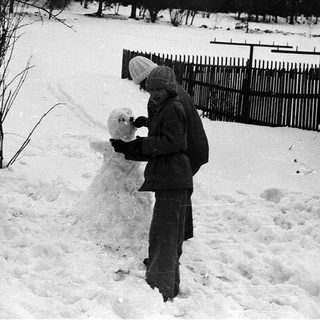 Child building snowman in winter landscape.