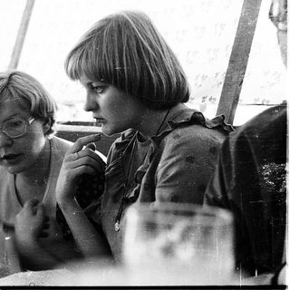 Three women intently reading newspapers outdoors.