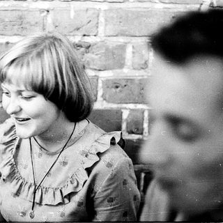 Young girl smiling indoors near brick wall.