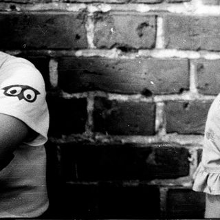 Young girl smiling indoors near brick wall.