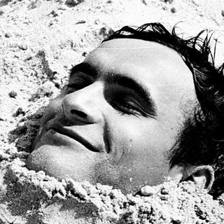 Man buried in sand, partially covered.