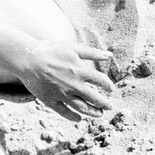Man buried in sand, partially covered.