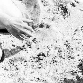Man buried in sand, partially covered.
