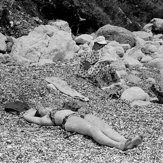 Person lying on gravel near seated individual.