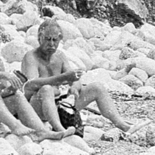 Two people sitting on rocky beach.