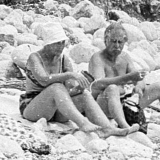 Two people sitting on rocky beach.