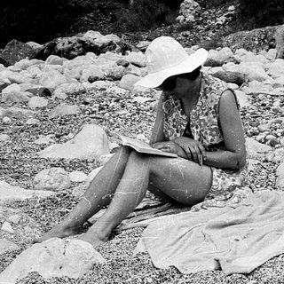 Person reading outdoors on rocky terrain.