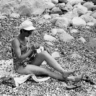 Woman relaxing outdoors on towel, eating.