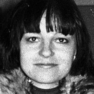 Woman standing in doorway wearing winter coat.