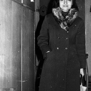 Woman standing in doorway wearing winter coat.