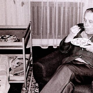 Man eating food alone indoors in vintage setting.