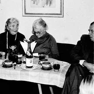 Three elderly women enjoying a meal together indoors.
