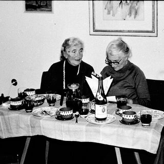 Three elderly women enjoying a meal together indoors.