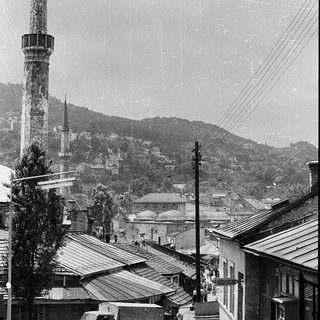 Historic town scene with minaret and old vehicles.