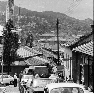 Historic town scene with minaret and old vehicles.