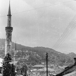 Historic town scene with minaret and old vehicles.