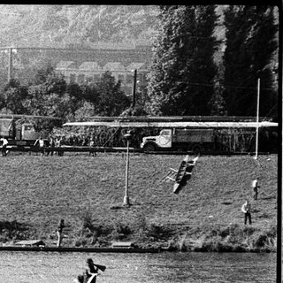 Rowing team practicing on a river near parked buses.