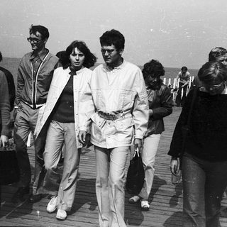 Group of people walking outdoors in retro 1970s-80s attire.